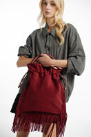 ISIDORA MALVA Elena suede top handle bag with burgundy fringes, showcasing its textured suede material and stylish design.