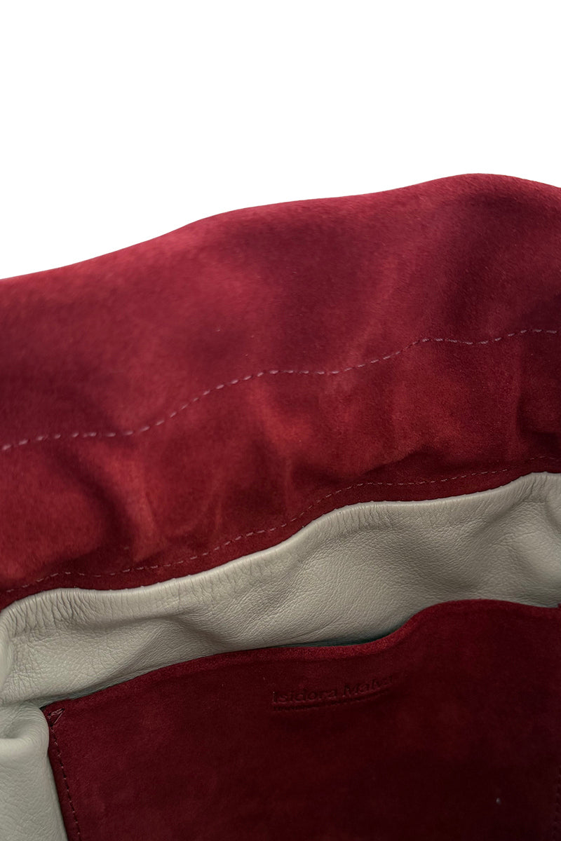 ISIDORA MALVA Elena suede top handle bag with burgundy fringes and gold hardware, showcasing its stylish design and textured material.