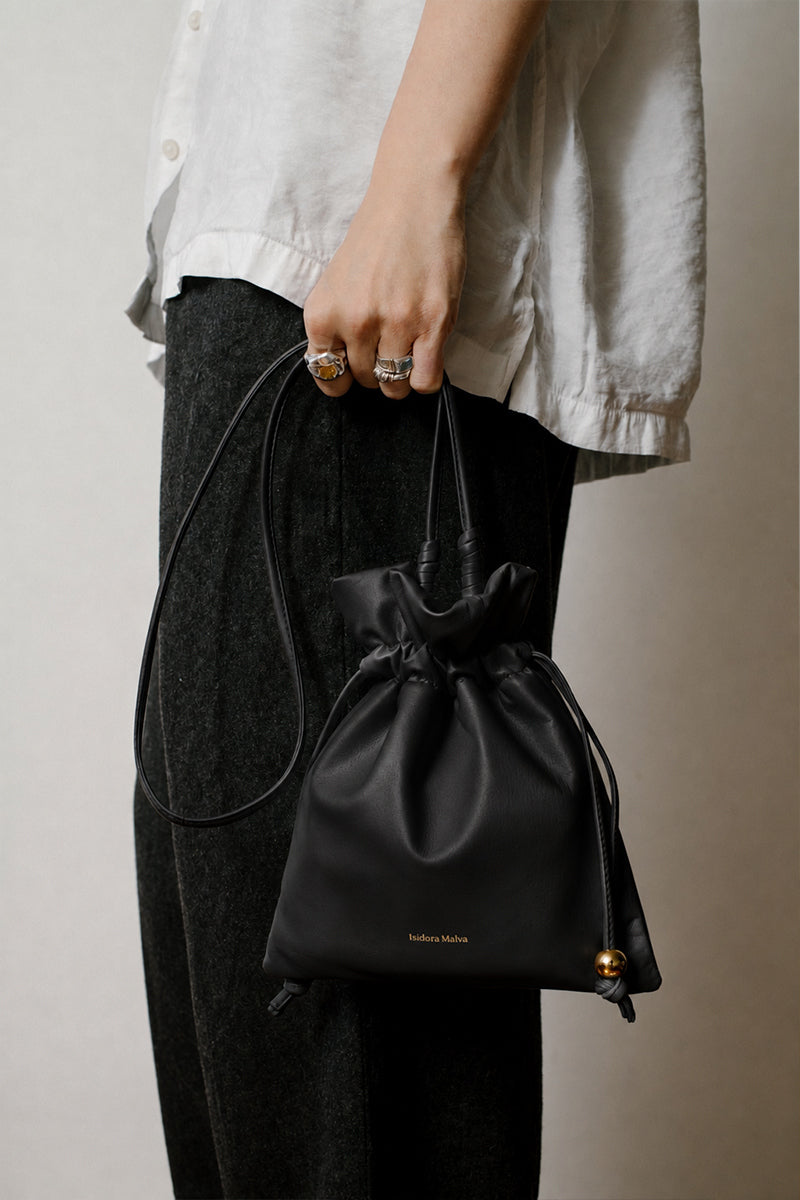 Black ISIDORA MALVA Elena mini pouch shoulder bag with a sleek design and shoulder strap, ideal for stylish everyday use.