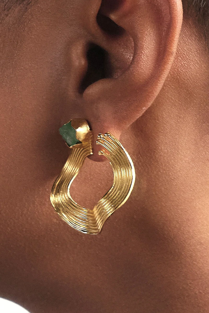 Gold earrings featuring open mini wave design with emerald accents from Fenomena.