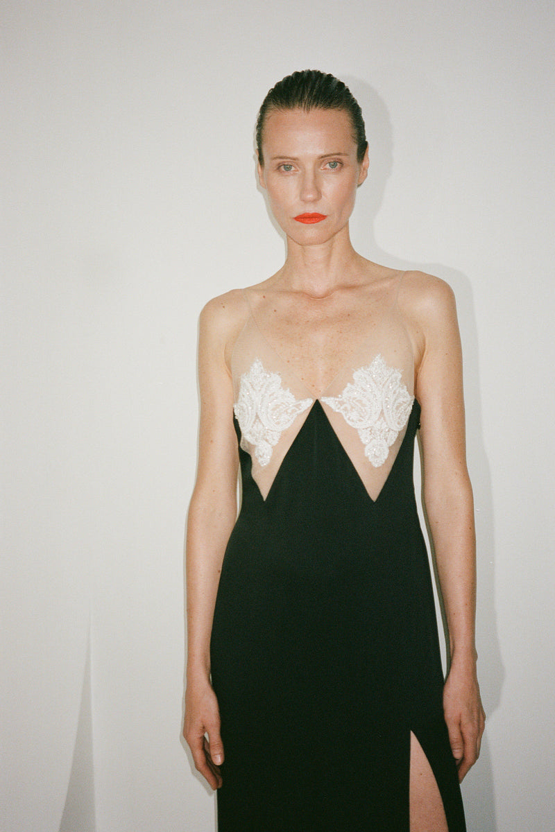 Black Nué Perla maxi dress displayed on a hanger, showcasing its elegant flowing fabric and full-length design.