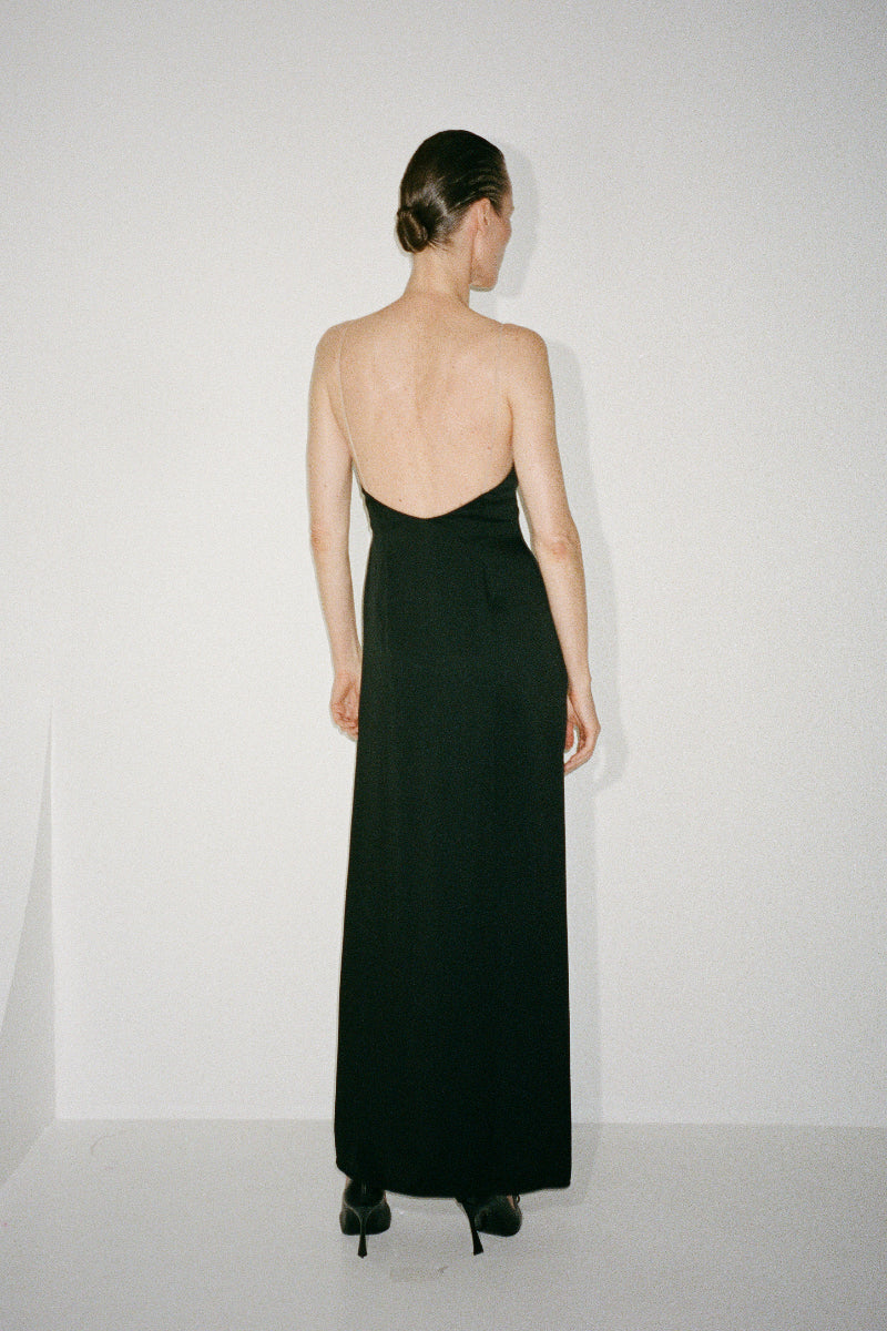 Black Nué Perla maxi dress displayed on a hanger, showcasing its elegant flowing fabric and classic silhouette.