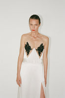 White Nué Perla maxi dress displayed on a hanger with flowing fabric and elegant design.