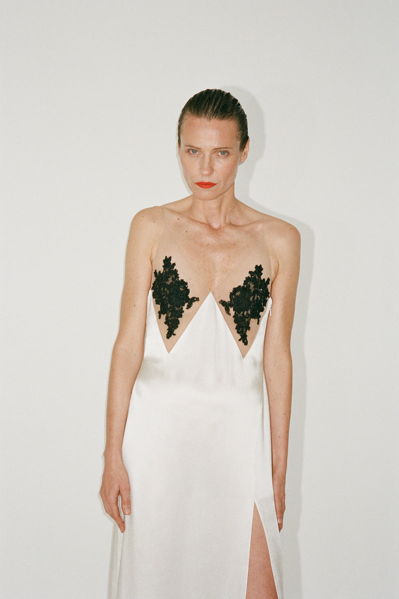 White Nué Perla maxi dress displayed on a hanger with flowing fabric and elegant design.
