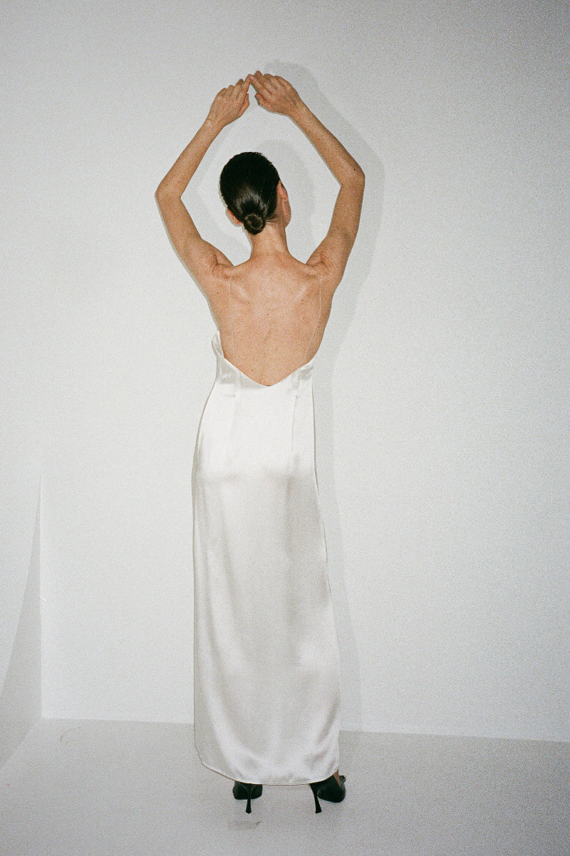 Nué Perla white maxi dress displayed on a hanger, featuring flowing fabric and elegant design for stylish summer or occasion wear.