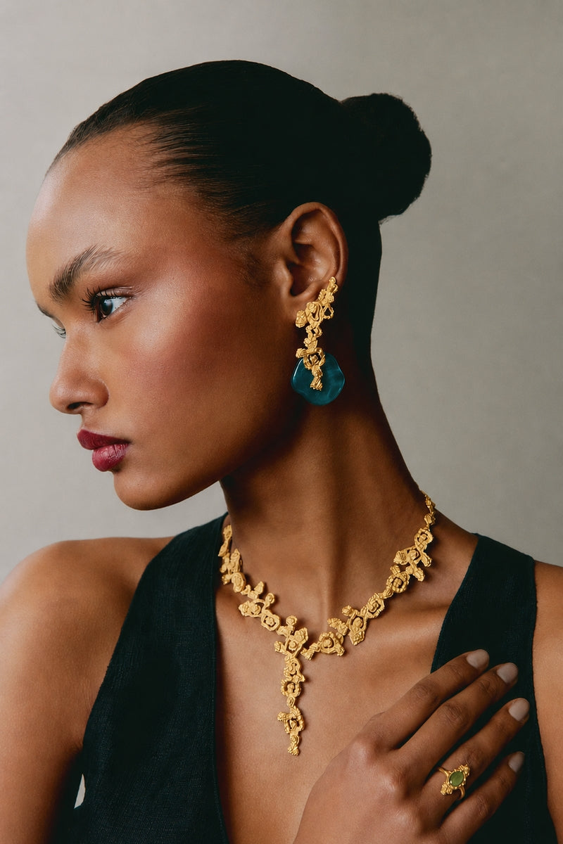 Jude Benhalim erosion earrings in gold and teal with a textured, organic design, shown close-up on a white background.