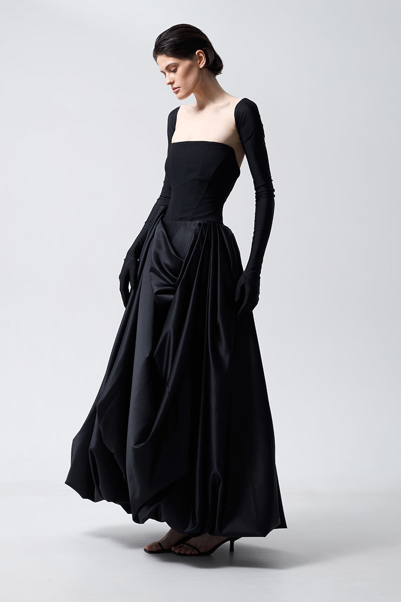 Black asymmetrical gown by Monetre, featuring a stylish uneven hem and elegant design, shown on a model.