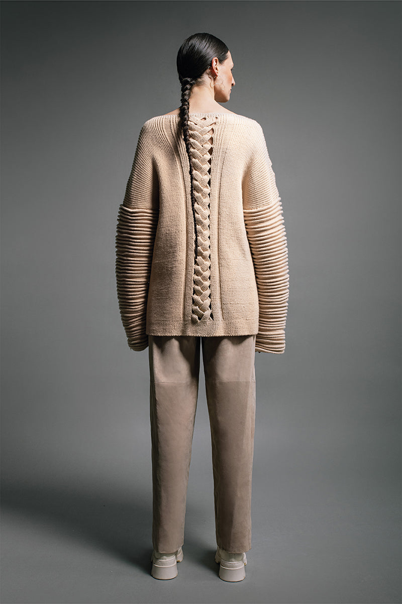 Ivory flat braided knitted sweater with accordion sleeves by MAZ Manuela Álvarez, showcasing textured knit and stylish design.