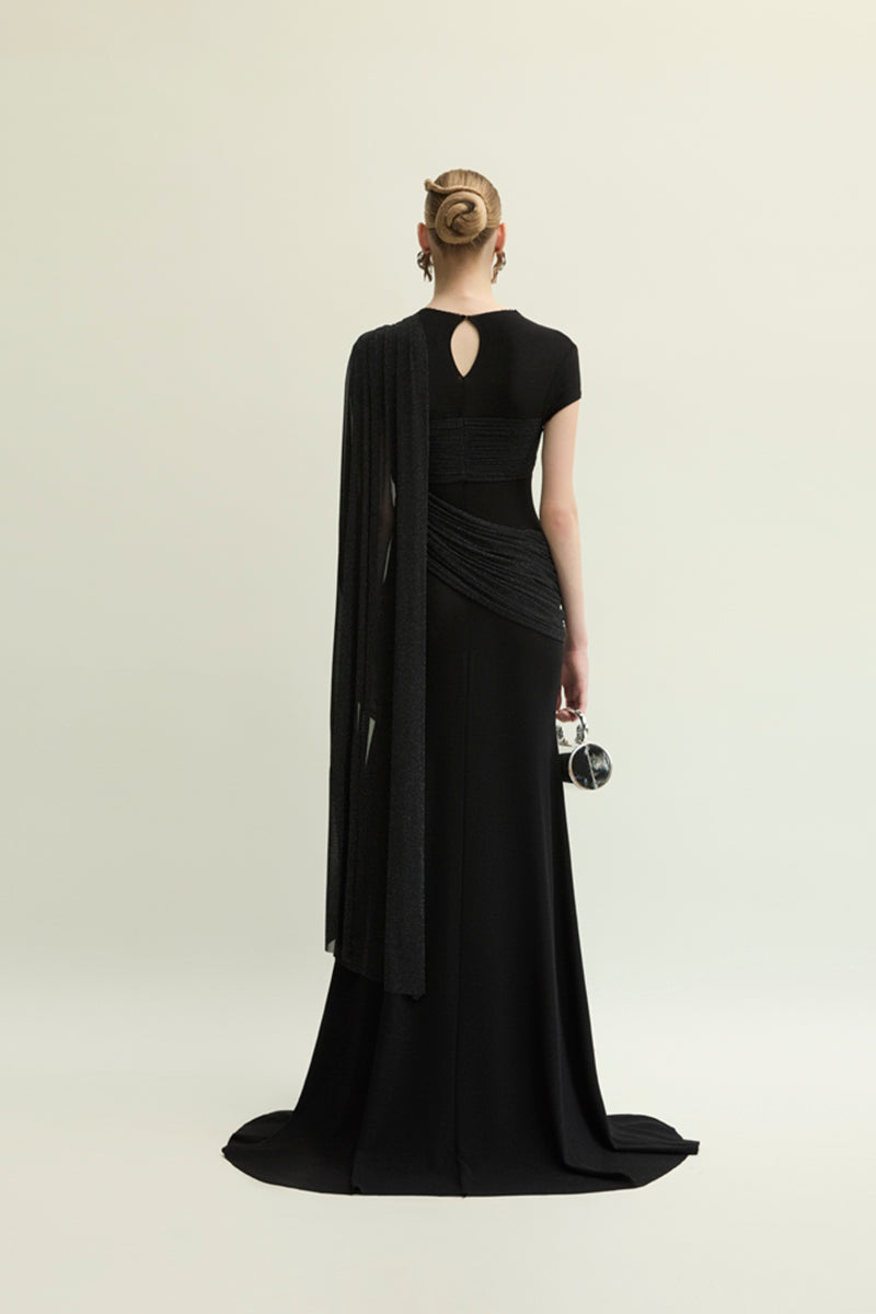 Elegant black Jenny K Tran Freya gown with a flowing design, showcased on a model in a stylish indoor setting.