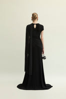Elegant black Jenny K Tran Freya gown with a flowing design, showcased on a model in a stylish indoor setting.
