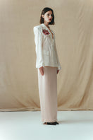 Sean Sheila blush satin maxi skirt displayed from a side view, showcasing its smooth fabric and flowing silhouette.