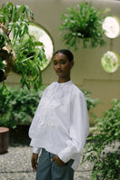 White ANA + MARIA Fiora top displayed on a model, showcasing its stylish design and fabric details.
