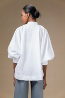 White Fiora top by ANA + MARIA displayed on a model, showcasing its stylish design and fit.