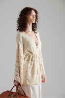 Cream-colored MIA cardigan by First Born Knits, featuring a soft knit texture and a relaxed fit, displayed on a hanger.