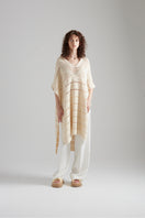 Knit poncho top by First Born Knits featuring cozy, textured knit fabric in neutral tones, styled as a fashionable layered garment.