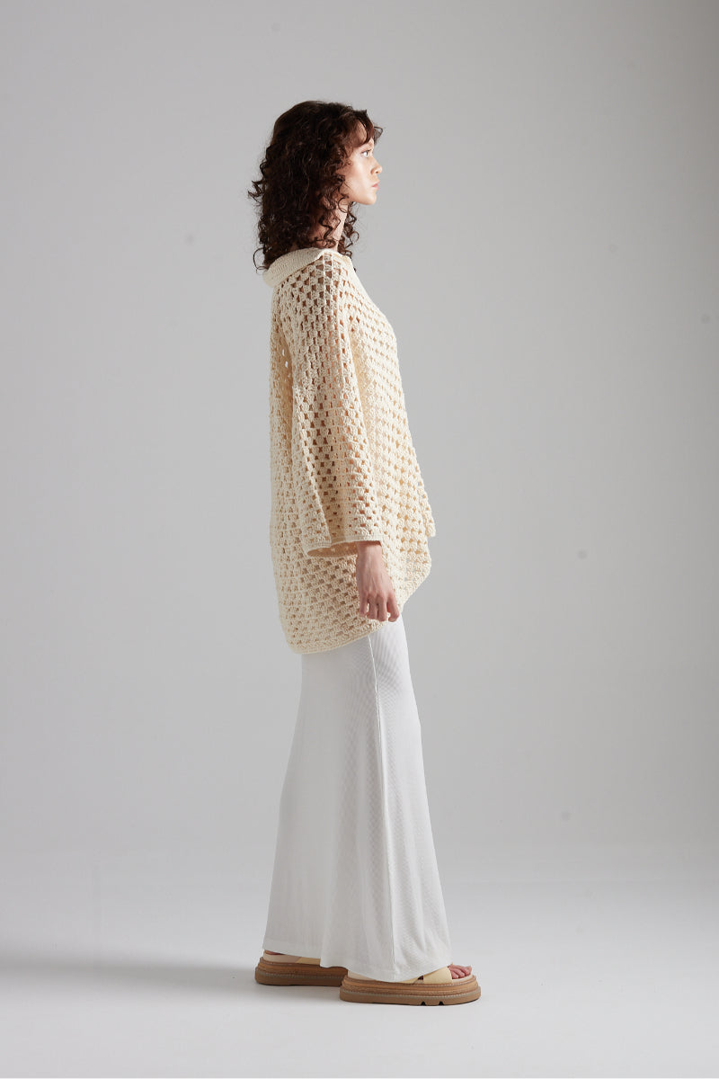 First Born Knits CELINE polo top in neutral color, featuring a classic collar and ribbed cuffs, displayed on a hanger.
