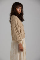 Light beige First Born Knits Lulu cardigan with button details, displayed flat on a neutral background.