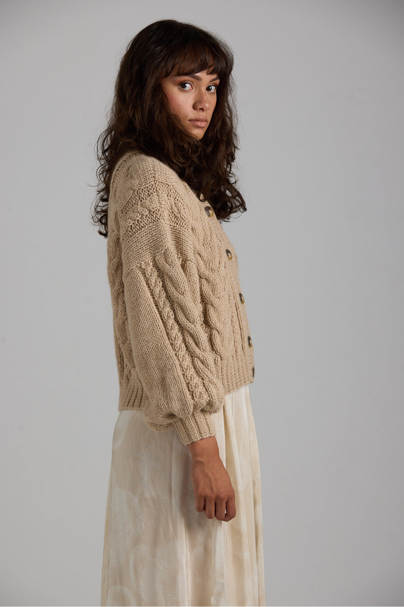 Light beige First Born Knits Lulu cardigan with button details, displayed flat on a neutral background.