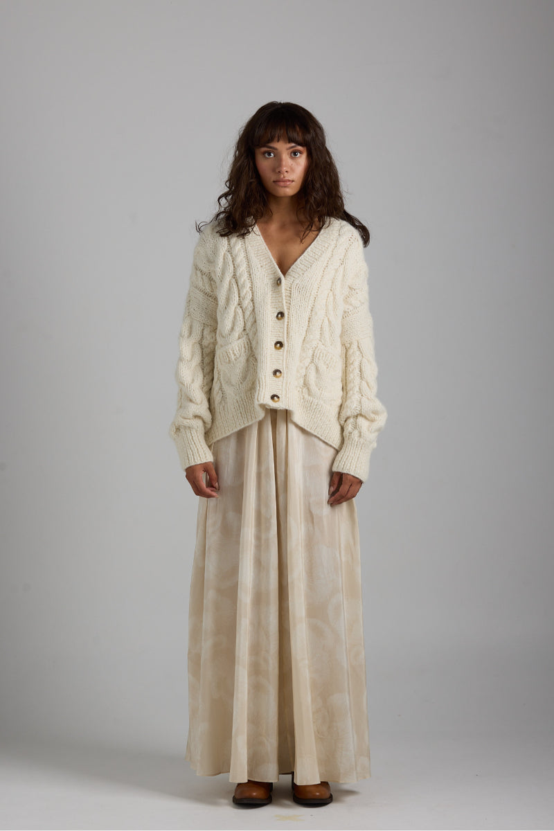 Light beige First Born Knits Paris Cardigan with button closure, soft knit fabric, and classic design.