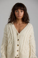 Cream-colored Paris cardigan by First Born Knits, featuring a cozy knit texture and classic button-front design.
