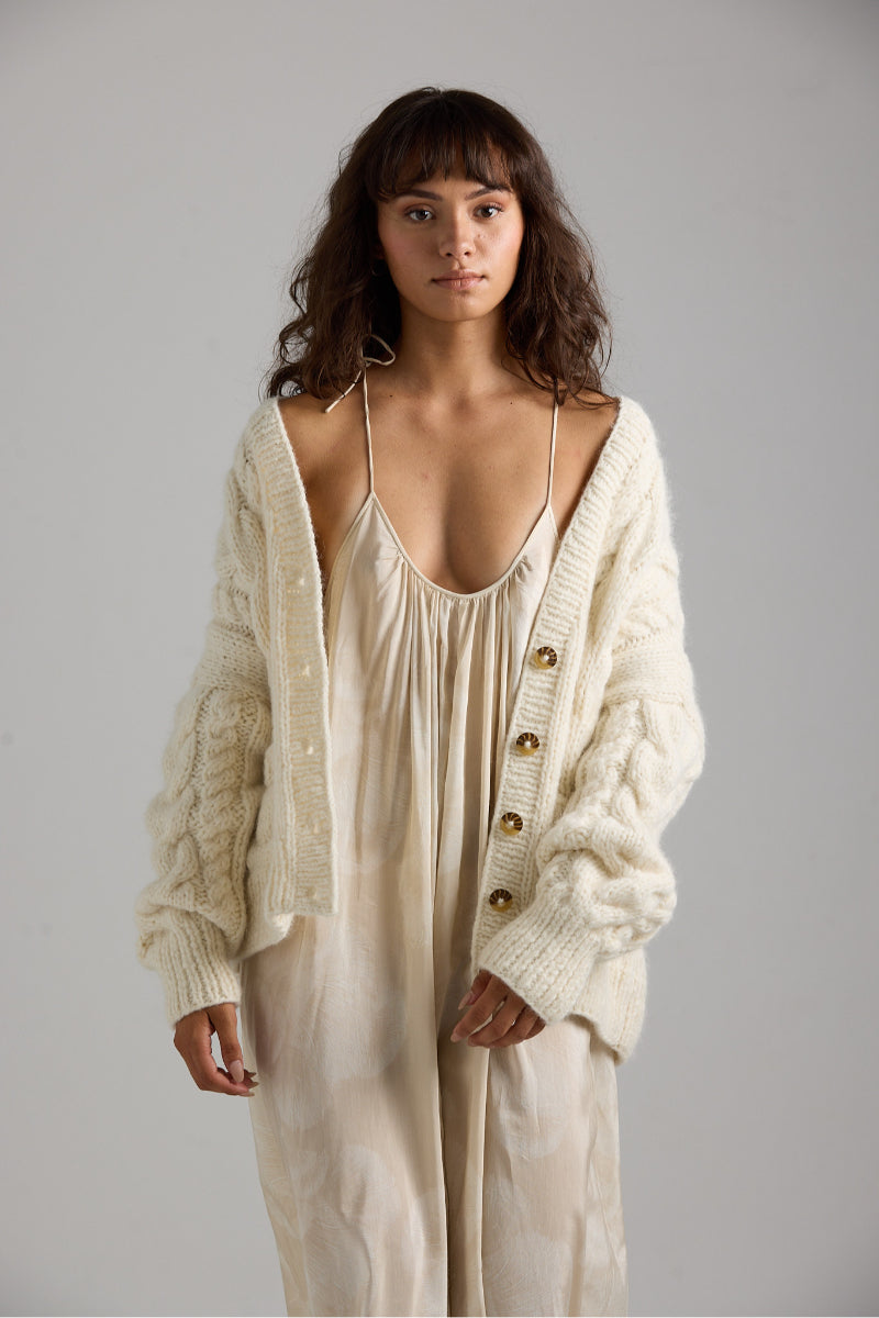 Light beige Paris cardigan by First Born Knits with a cozy, button-up design and ribbed cuffs, displayed on a neutral background.