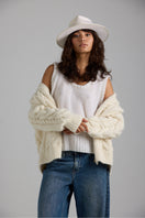 First Born Knits Paris cardigan displayed on a hanger, featuring a cozy, knit design in neutral tones.