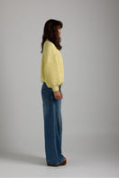 Cream-colored shell sweater by First Born Knits, featuring a cozy knit design and ribbed cuffs, perfect for casual wear.