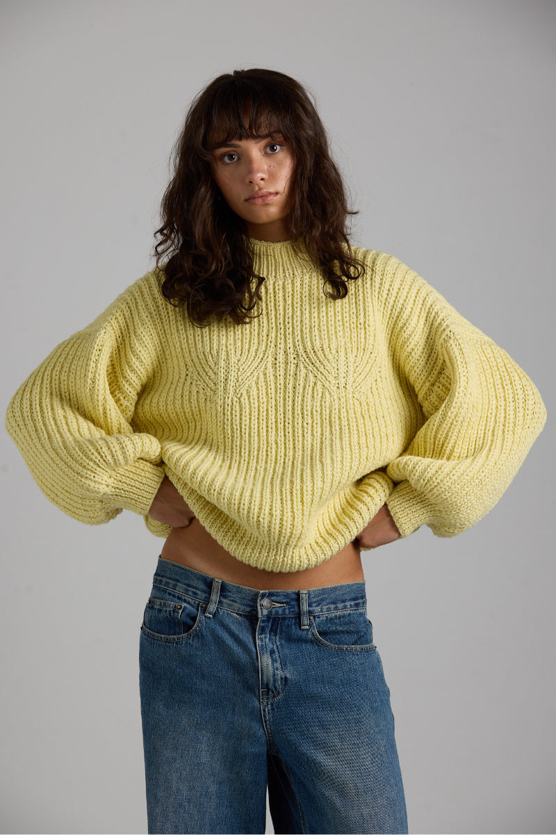 Cream-colored Shell Sweater from First Born Knits featuring a cozy, textured knit pattern and ribbed cuffs.