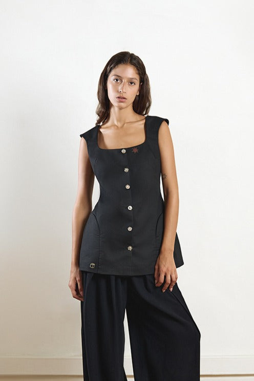 Black fixed corset top by YASSMIN SALEH featuring a fitted design and front closure, styled for a fashionable look.