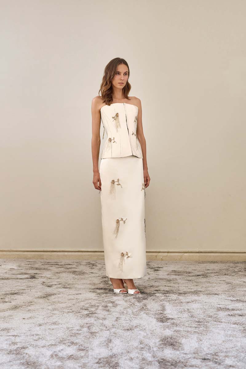 White flare corset top by YASSMIN SALEH featuring a fitted bodice and flared hem, styled in a front view.