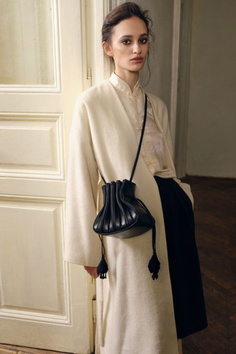 Black TUEAM'S Fleur top handle bag featuring a sleek design with a structured silhouette and elegant floral accents.