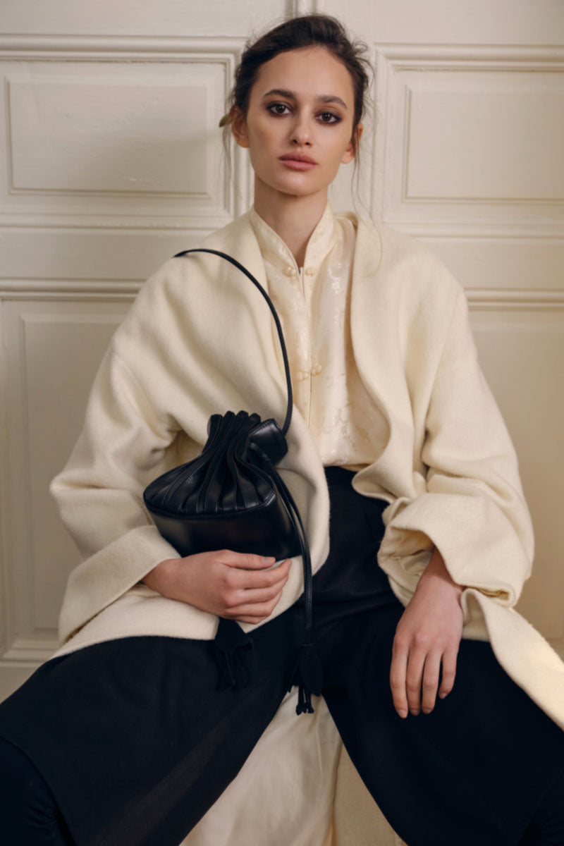 Black TUEAM'S Fleur top handle bag with elegant floral design and sturdy handle, perfect for stylish everyday use.