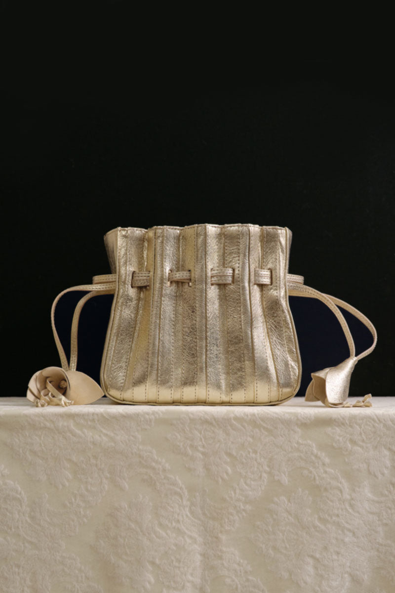 Gold Fleur bag by TUEAM'S, a stylish top handle bag with elegant floral detailing and a chic gold finish.