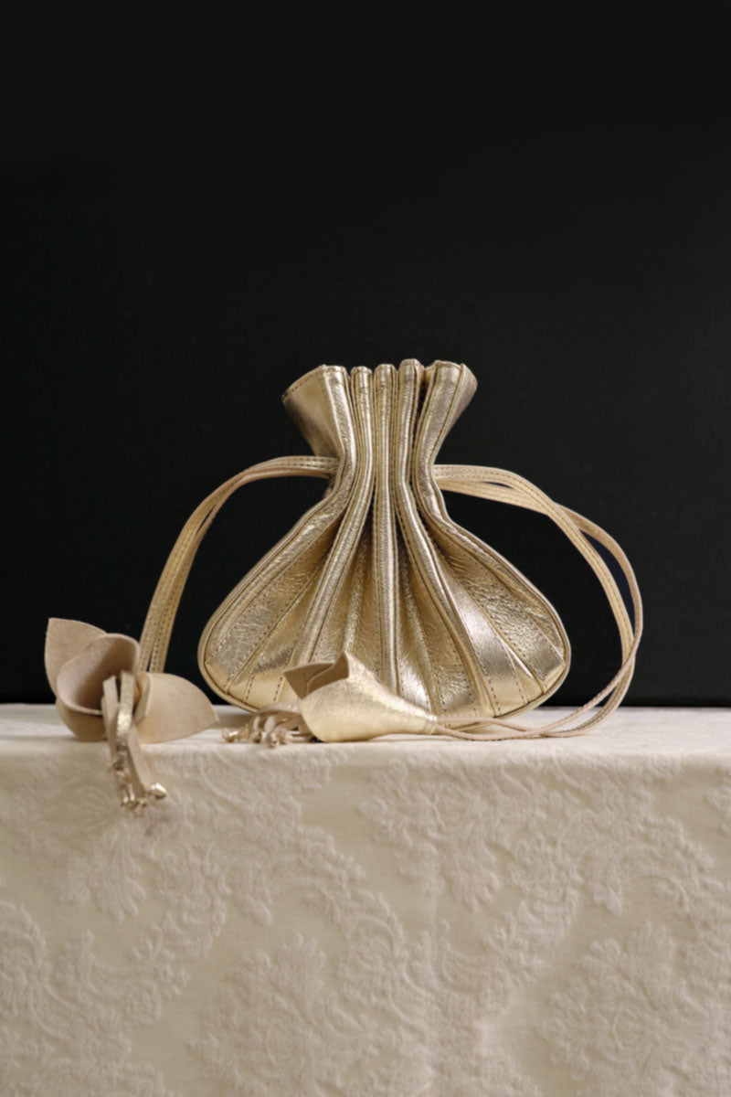 Gold TUEAM'S Fleur top handle bag with elegant floral design and structured shape, perfect for stylish everyday use.