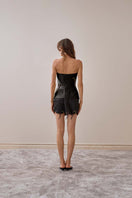 Back view of YASSMIN SALEH black fold mini skirt showing its stylish pleats and sleek design.