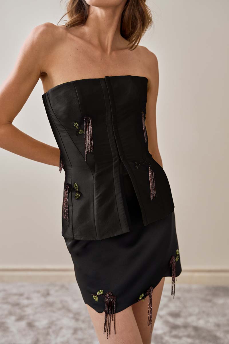 Close-up of YASSMIN SALEH black fold mini skirt showing the fabric texture and stylish fold design.