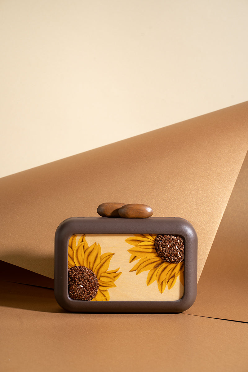 Brown clutch with sunflower embroidery from Sy&Vie, featuring intricate floral details and a sleek design.