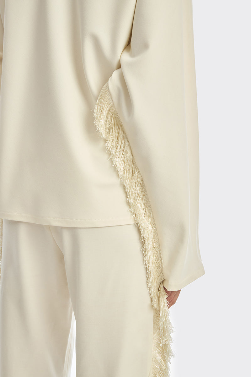 Ivory white long sleeve top with thread fringe details from Stolen Stores, showcasing a stylish and bohemian-inspired blouse.