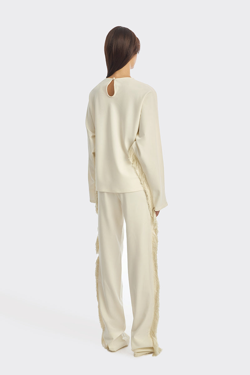 Ivory white long-sleeve top with fringe details from Stolen Stores, featuring a bohemian style and relaxed fit.
