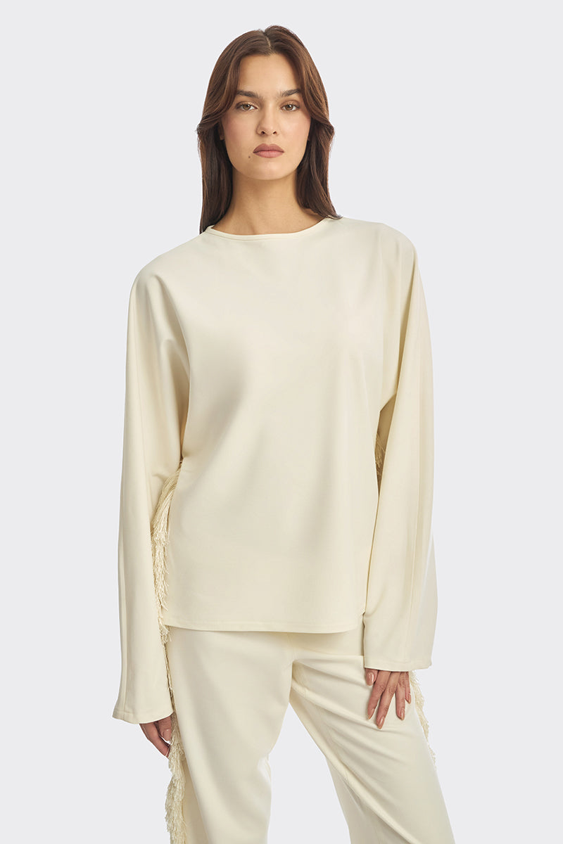 Ivory white long-sleeve top with thread fringe detailing from Stolen Stores, showcasing a stylish boho-inspired blouse.