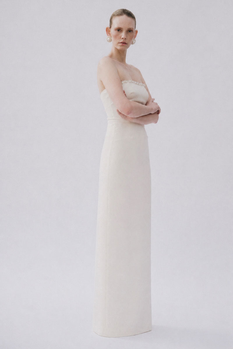 White gown from Gigii's LOTTE DRESS collection, elegant gown with flowing fabric and detailed design, perfect for formal occasions.