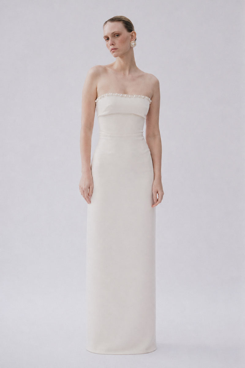 White Lotte gown by Gigii's, elegant floor-length dress with flowing fabric and subtle detailing, perfect for formal occasions.