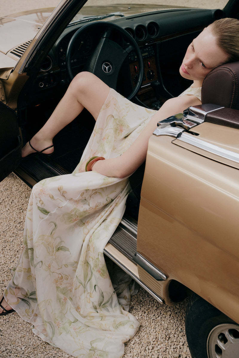 Gigii's Zeta floral maxi dress displayed on a hanger with vibrant floral patterns and flowing fabric.