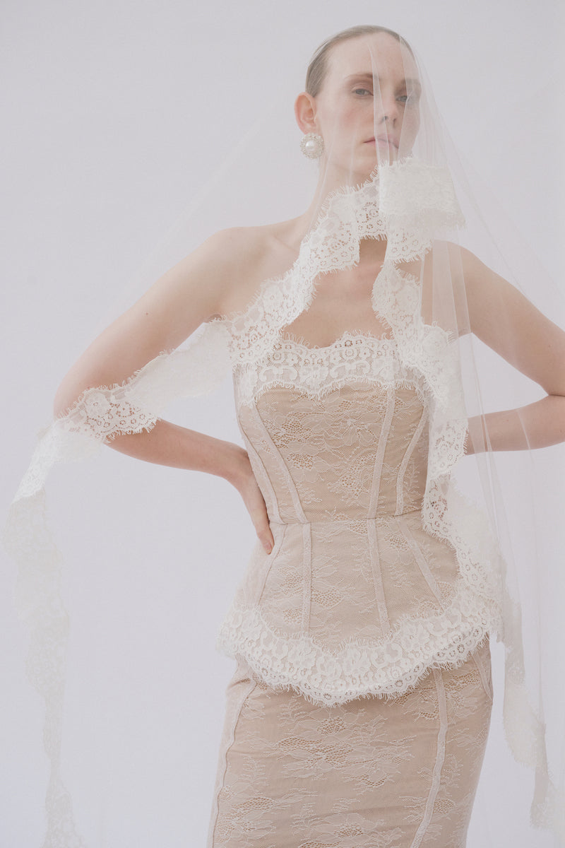 Elegant lace gown named Sabrina by Gigii's, featuring intricate lace details and a flowing silhouette.
