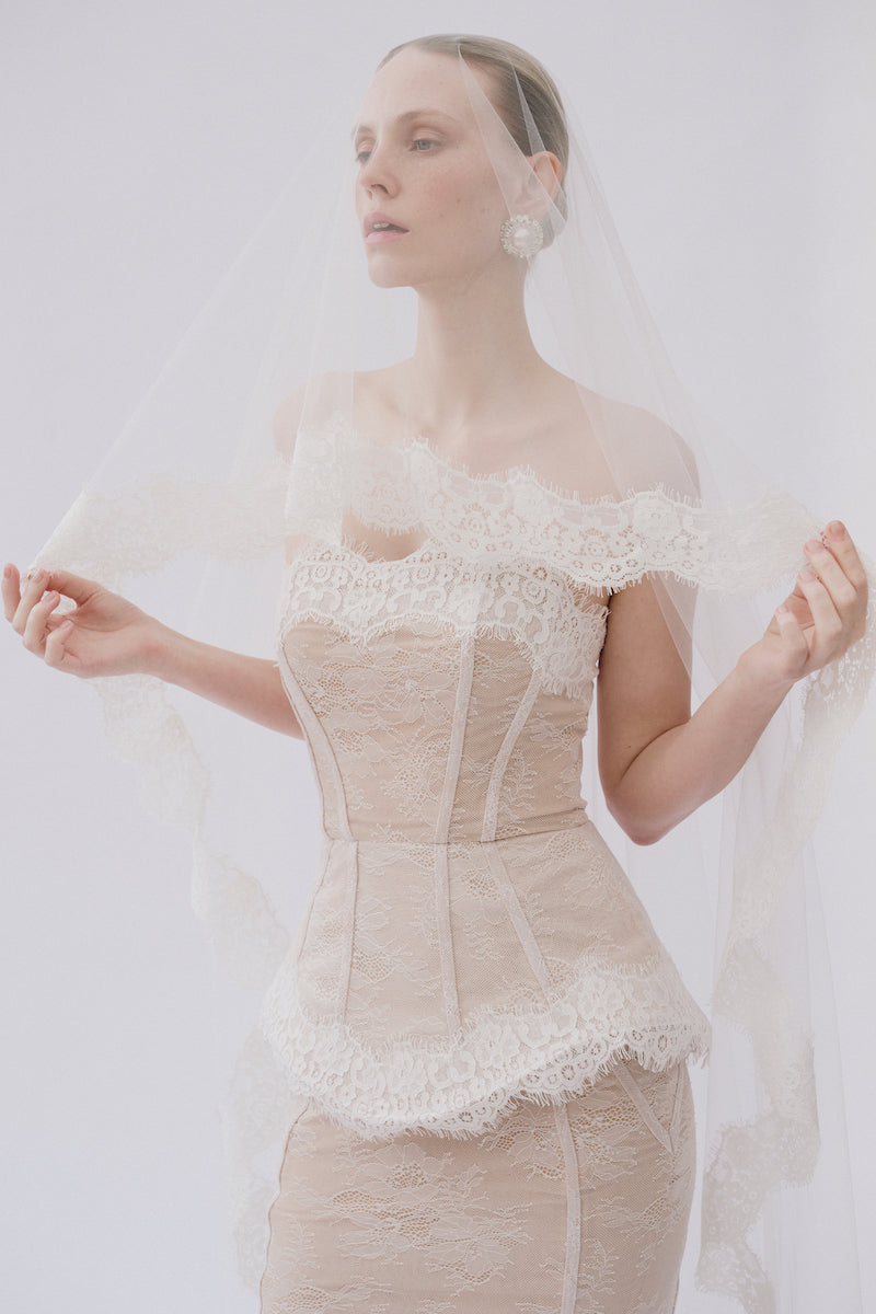 Elegant lace gown named Sabrina Dress by Gigii's, featuring intricate lace details and a flowing silhouette.