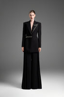 Black GVLUX multi-pleat wide-leg trousers, stylish pants with a relaxed fit and flowing fabric, shown on a model.