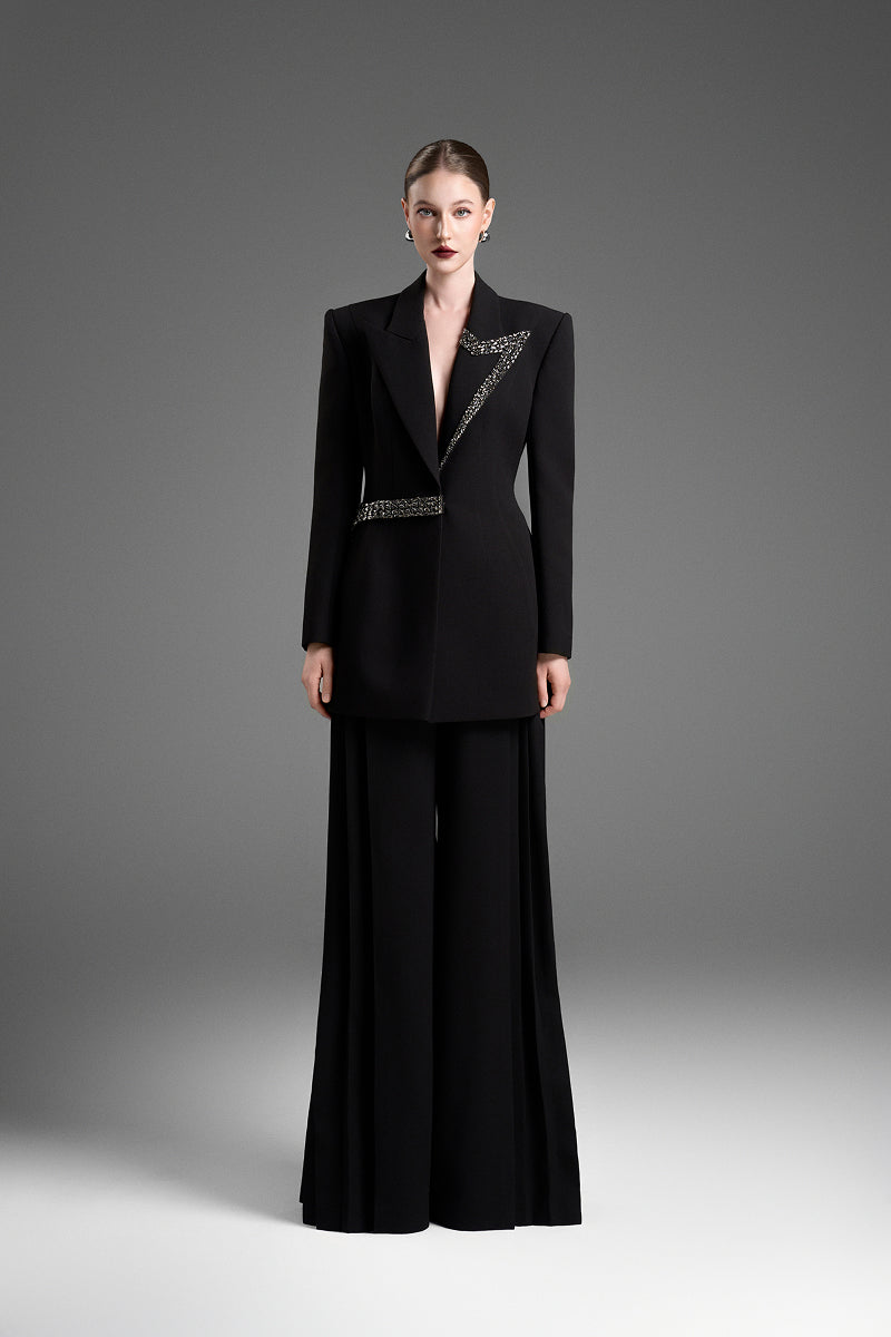 Black GVLUX multi-pleat wide-leg trousers, stylish pants with a relaxed fit and flowing fabric, shown on a model.