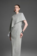 Light gray asymmetric draped cape sleeve maxi dress by GVLUX, featuring a sleek column silhouette and elegant draping details.