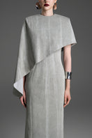 Light gray asymmetrical draped cape sleeve maxi dress by GVLUX, featuring a sleek column silhouette and elegant design.