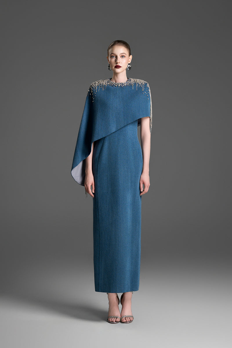Blue asymmetrical column maxi dress with draped cape sleeve by GVLUX, featuring flowing fabric and elegant design.